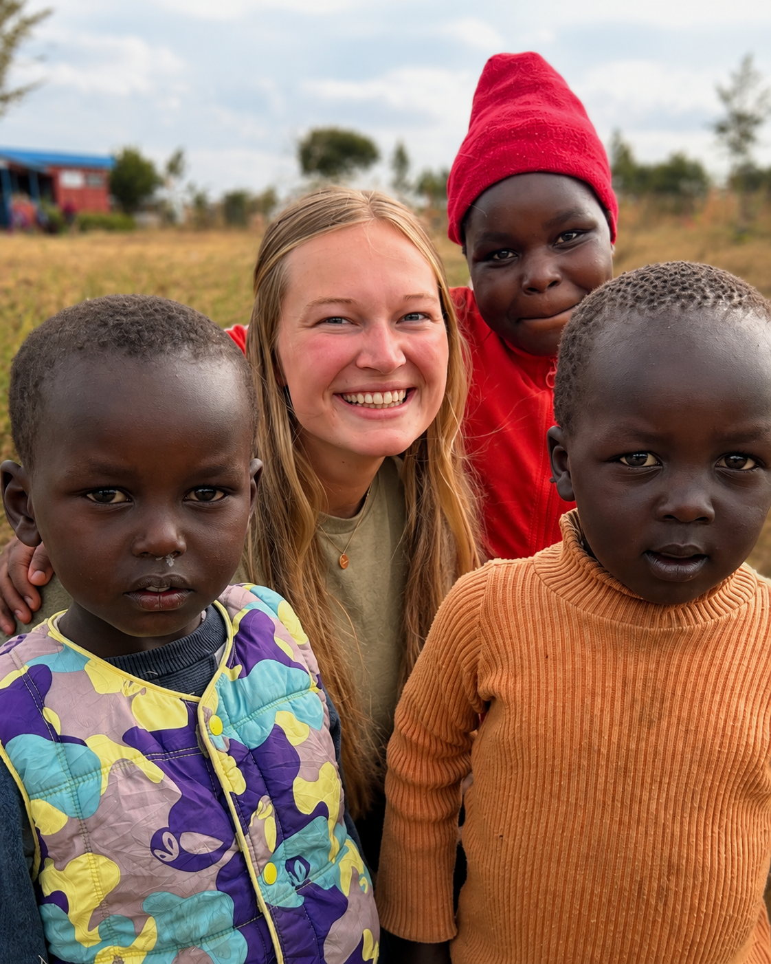 Maegan smiling with Kenyan children during a Helping Kenya Kids trip