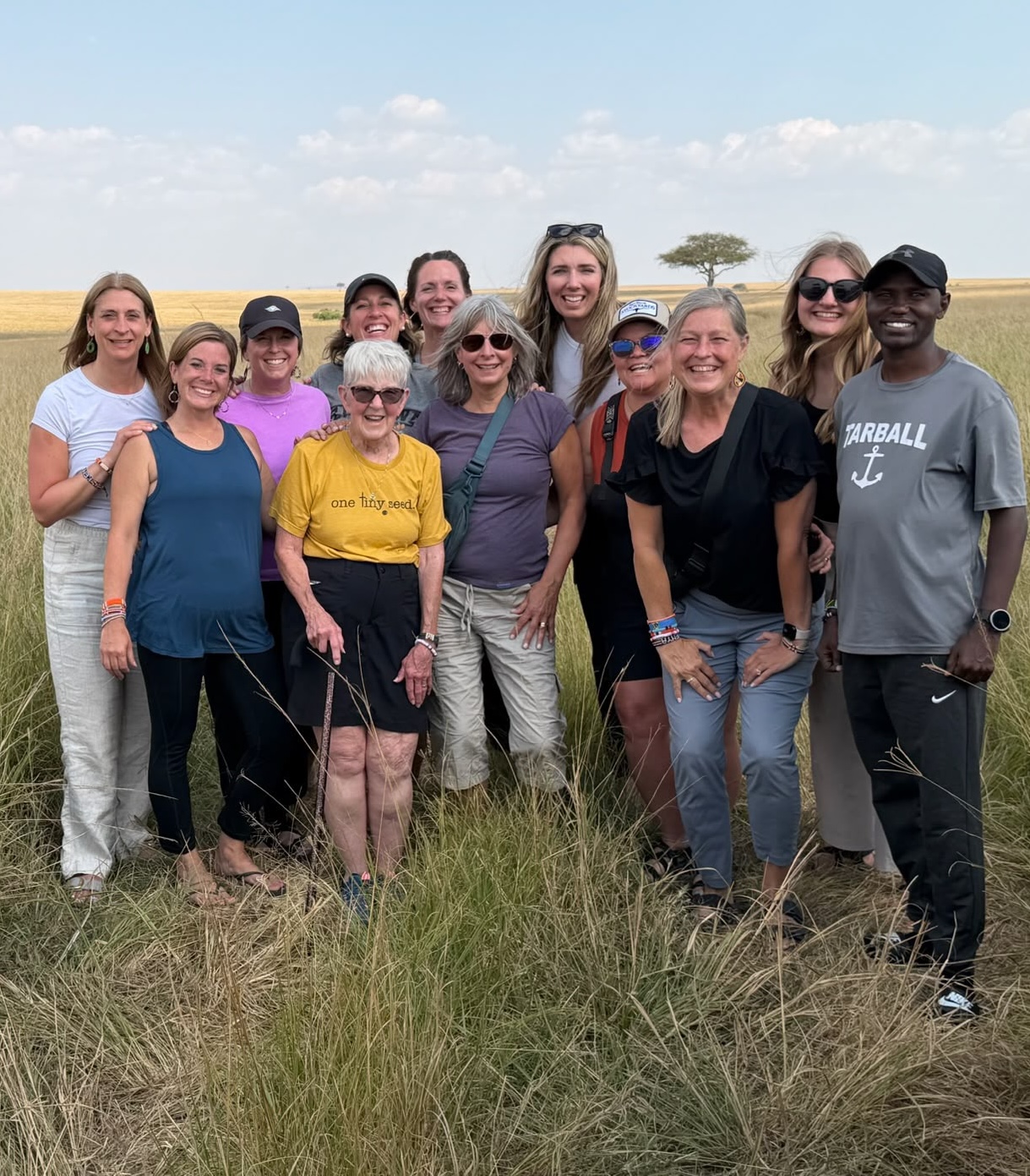 A Helping Kenya Kids travel group smiling together on the savanna