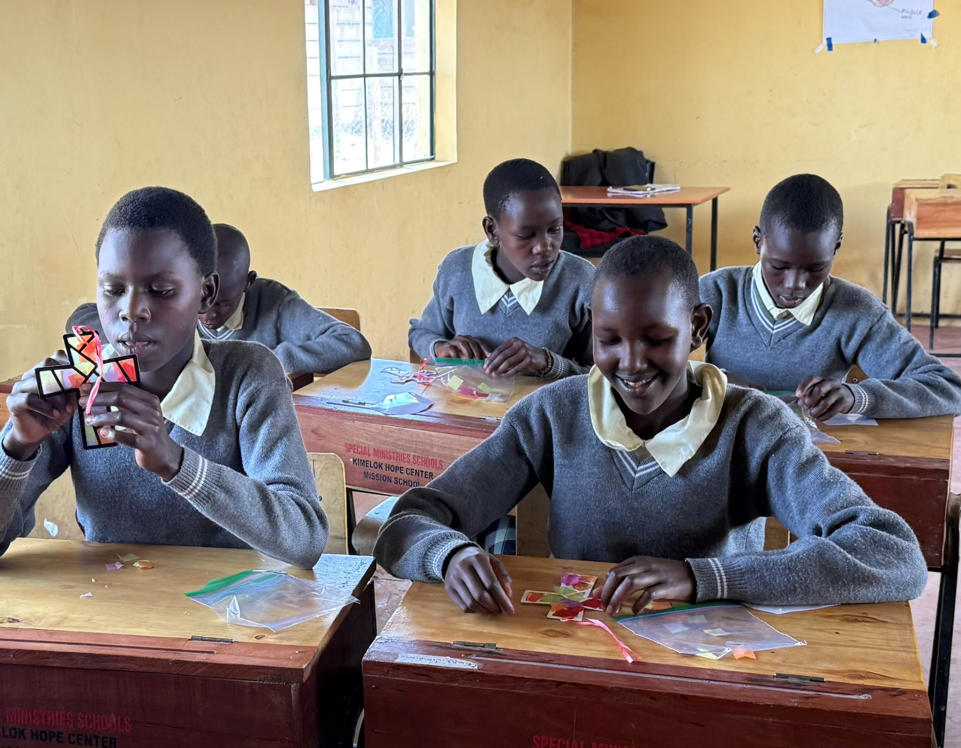 Students at the Kimelok Hope Center classroom working on cross crafts during a lesson