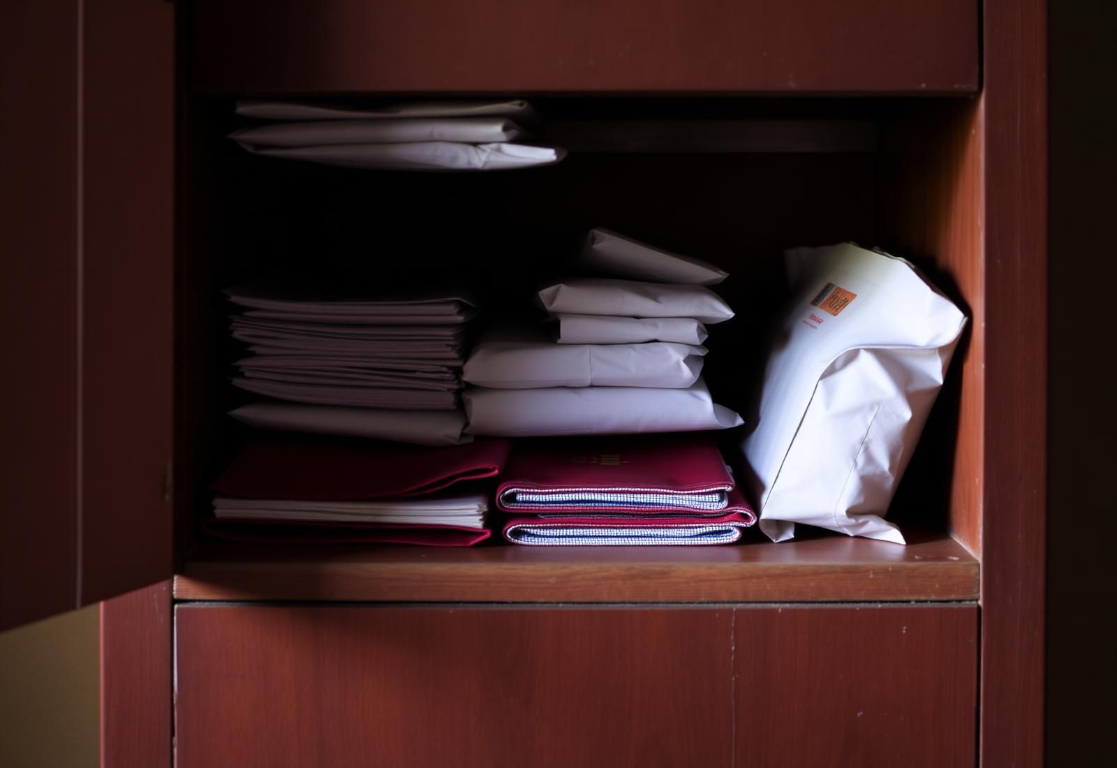 A simple classroom resource cabinet holding neatly folded supplies and paper-wrapped packets